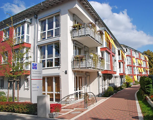 Modernes, 3-Stöckiges Wohngebäude mit vielen Balkons und Blick in einen gepflasterten Weg vor dem Gebäude
