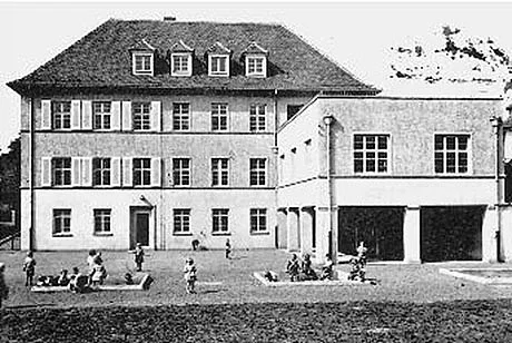 Schwarz-Weiß-Foto eines großen Kindergarten, davor einige Kinder